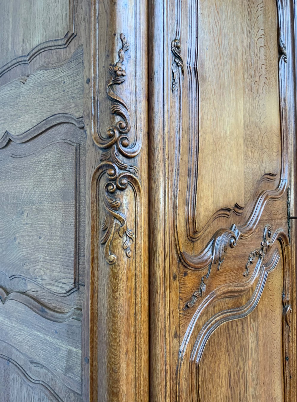 A large French Provincial carved oak armoire featuring double panelled doors, intricate cresting, brass hardware, and cabriole feet. View XV