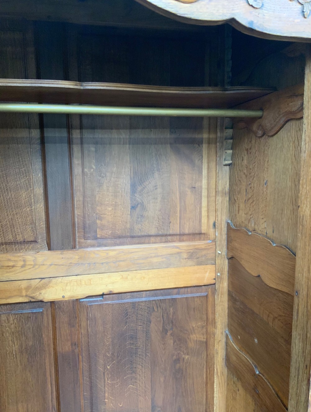 A large French Provincial carved oak armoire featuring double panelled doors, intricate cresting, brass hardware, and cabriole feet. View XVIII