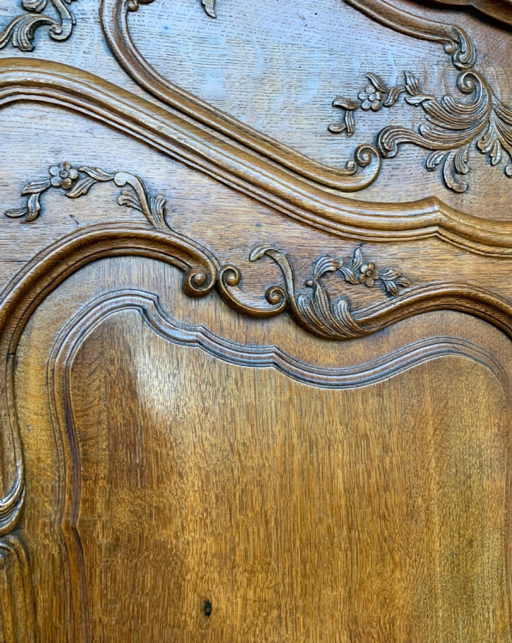 A large French Provincial carved oak armoire featuring double panelled doors, intricate cresting, brass hardware, and cabriole feet. View XIX