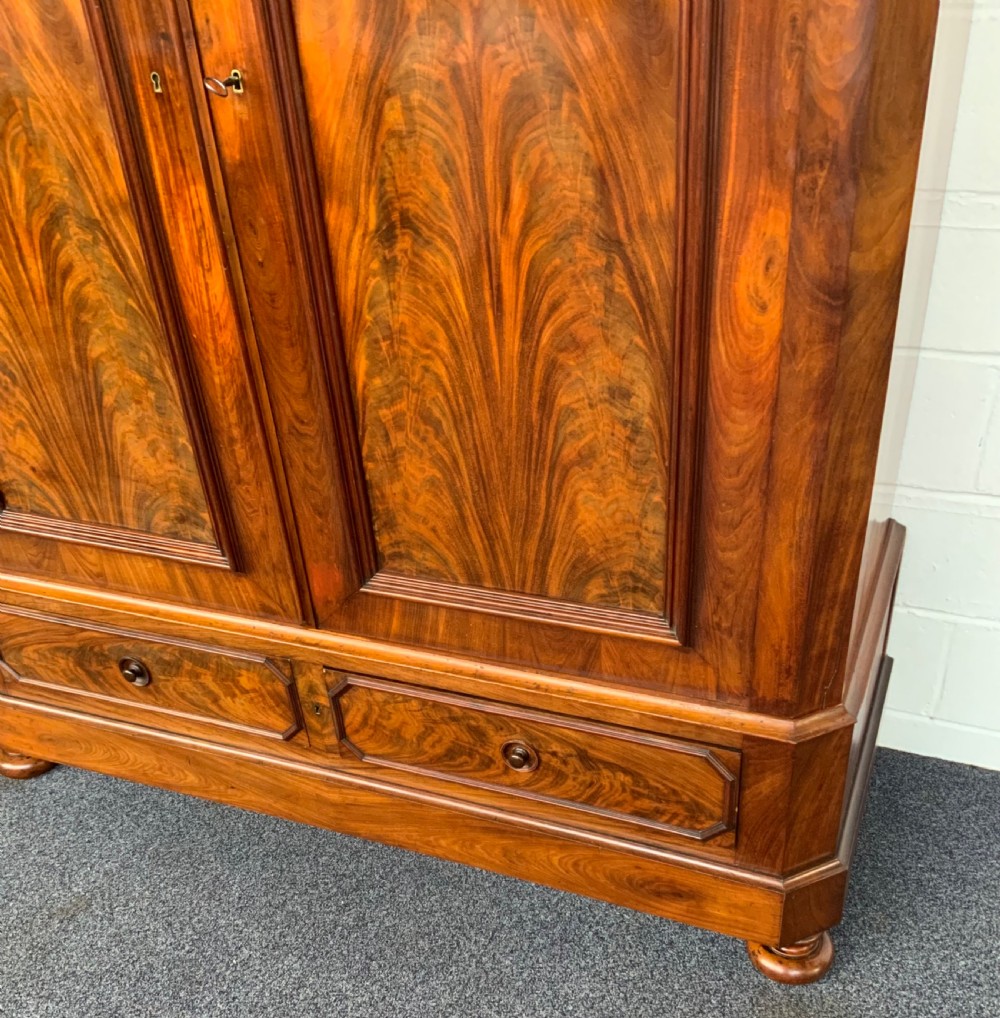 A 19th-century French mahogany armoire with flame-veneered double doors, a top moulding, two base drawers, and turned bun feet. View IV