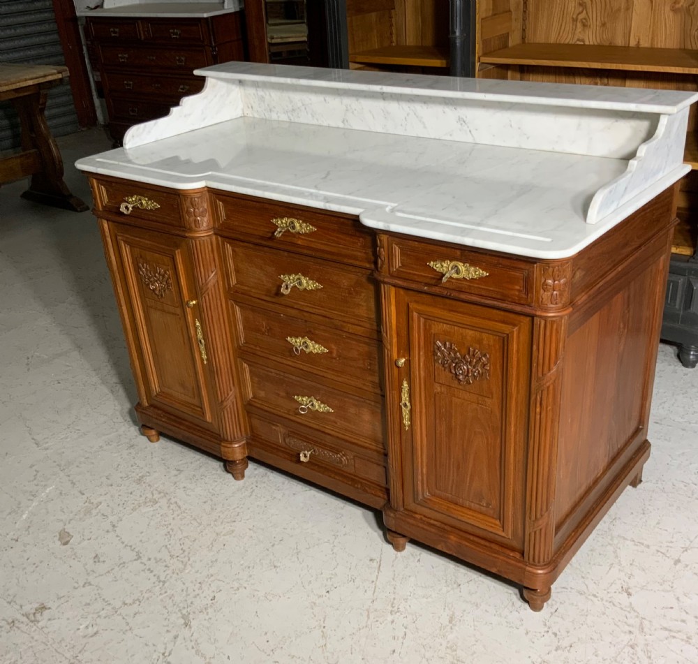 An antique mahogany French washstand featuring a white marble top, integrated arched mirror, multiple drawers, and side cupboards with brass handles. View II