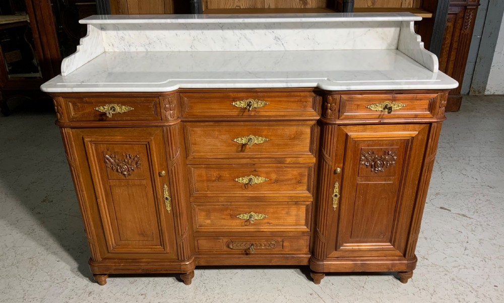 An antique mahogany French washstand featuring a white marble top, integrated arched mirror, multiple drawers, and side cupboards with brass handles. View III