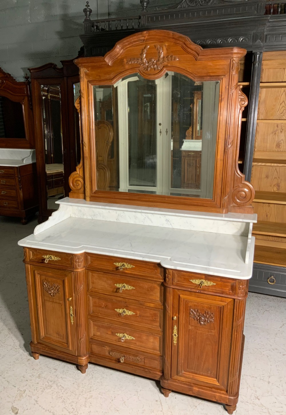 An antique mahogany French washstand featuring a white marble top, integrated arched mirror, multiple drawers, and side cupboards with brass handles. View XIV