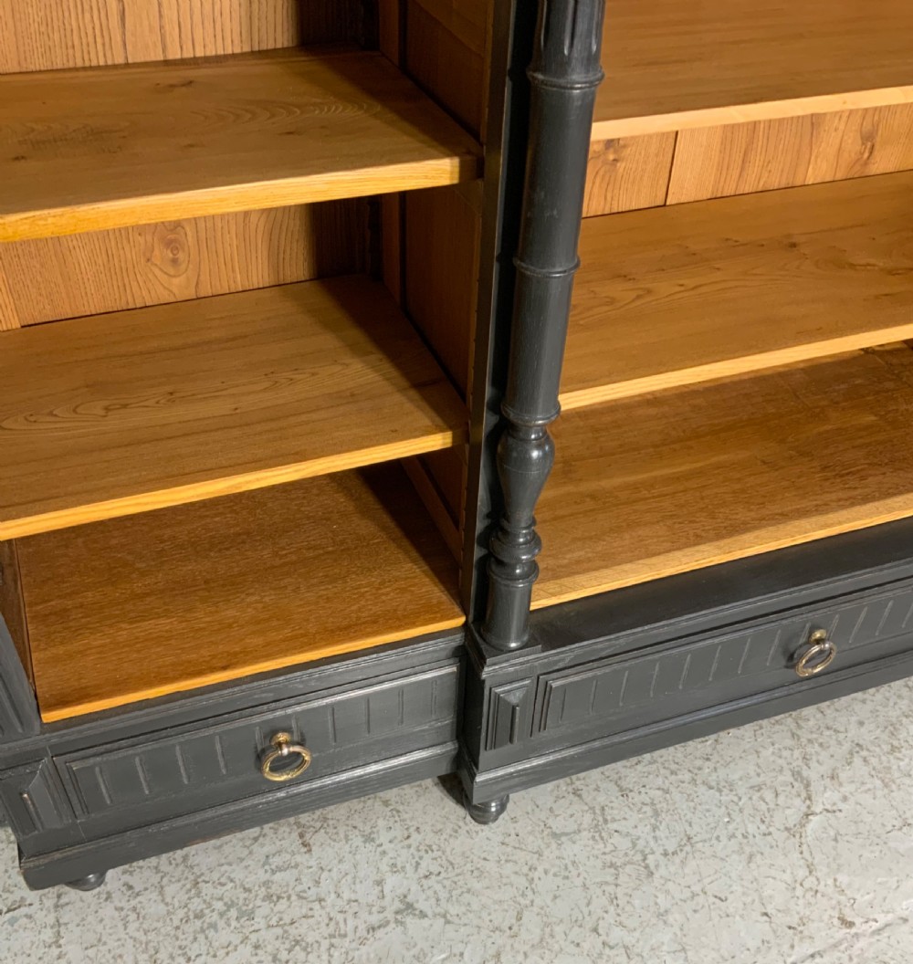 A large antique French open bookcase featuring a dark painted frame with carved shell cresting and finials, contrasting natural pine shelving, and three bottom drawers with brass handles. View XIV