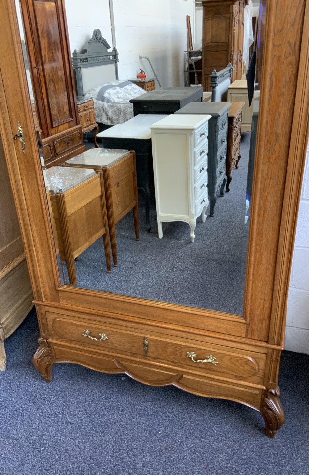 A tall French oak single-door armoire featuring an arched mirrored door, a carved cresting pediment, a bottom drawer, and cabriole feet. View II
