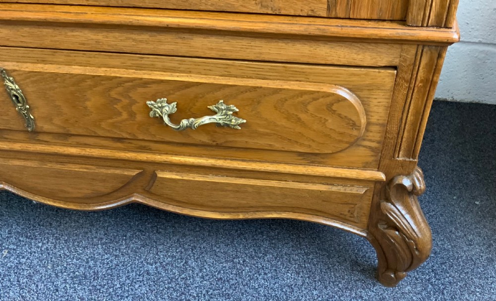 A tall French oak single-door armoire featuring an arched mirrored door, a carved cresting pediment, a bottom drawer, and cabriole feet. View VIII