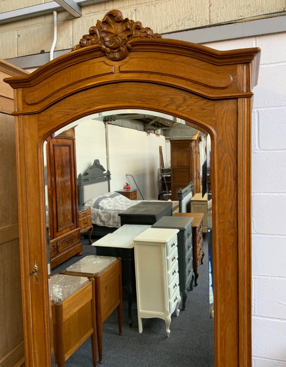 A tall French oak single-door armoire featuring an arched mirrored door, a carved cresting pediment, a bottom drawer, and cabriole feet. View IX