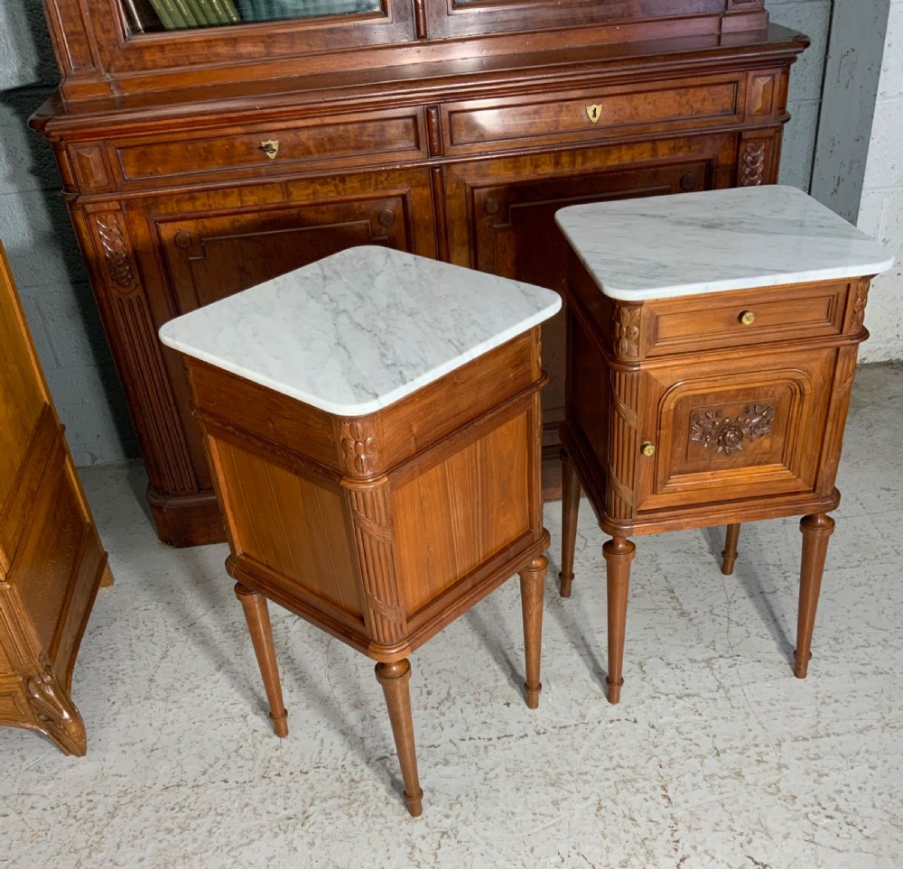 A pair of French Louis XVI style walnut bedside cabinets with grey-veined white marble tops, carved door panels, and turned legs. View VIII