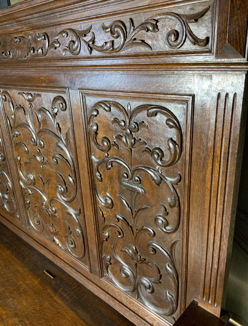 A carved dark oak French hall seat featuring a high backrest with scrollwork relief panels, turned arm spindles, and a hinged storage seat base. View IV