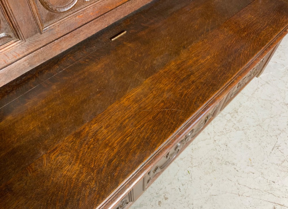 A carved dark oak French hall seat featuring a high backrest with scrollwork relief panels, turned arm spindles, and a hinged storage seat base. View VI