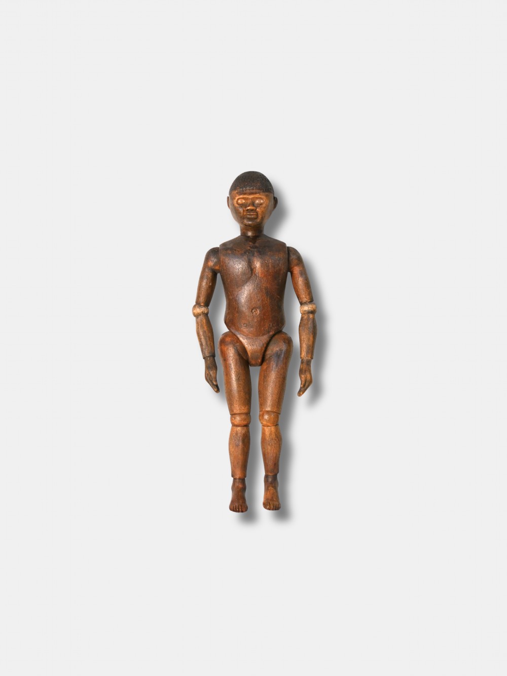 A carved dark wood articulated lay figure standing upright with jointed limbs.