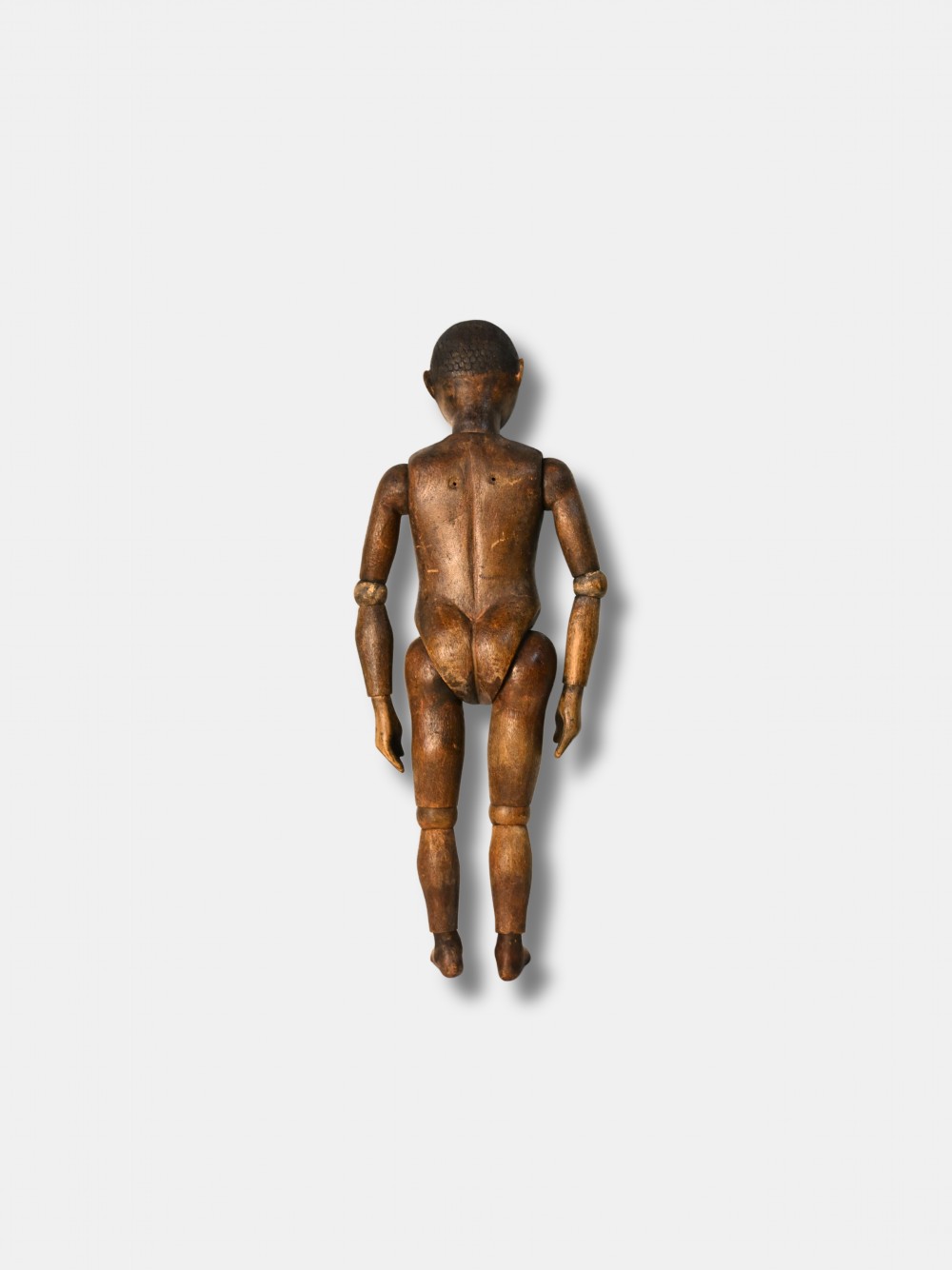 A carved dark wood articulated lay figure standing upright with jointed limbs. View II