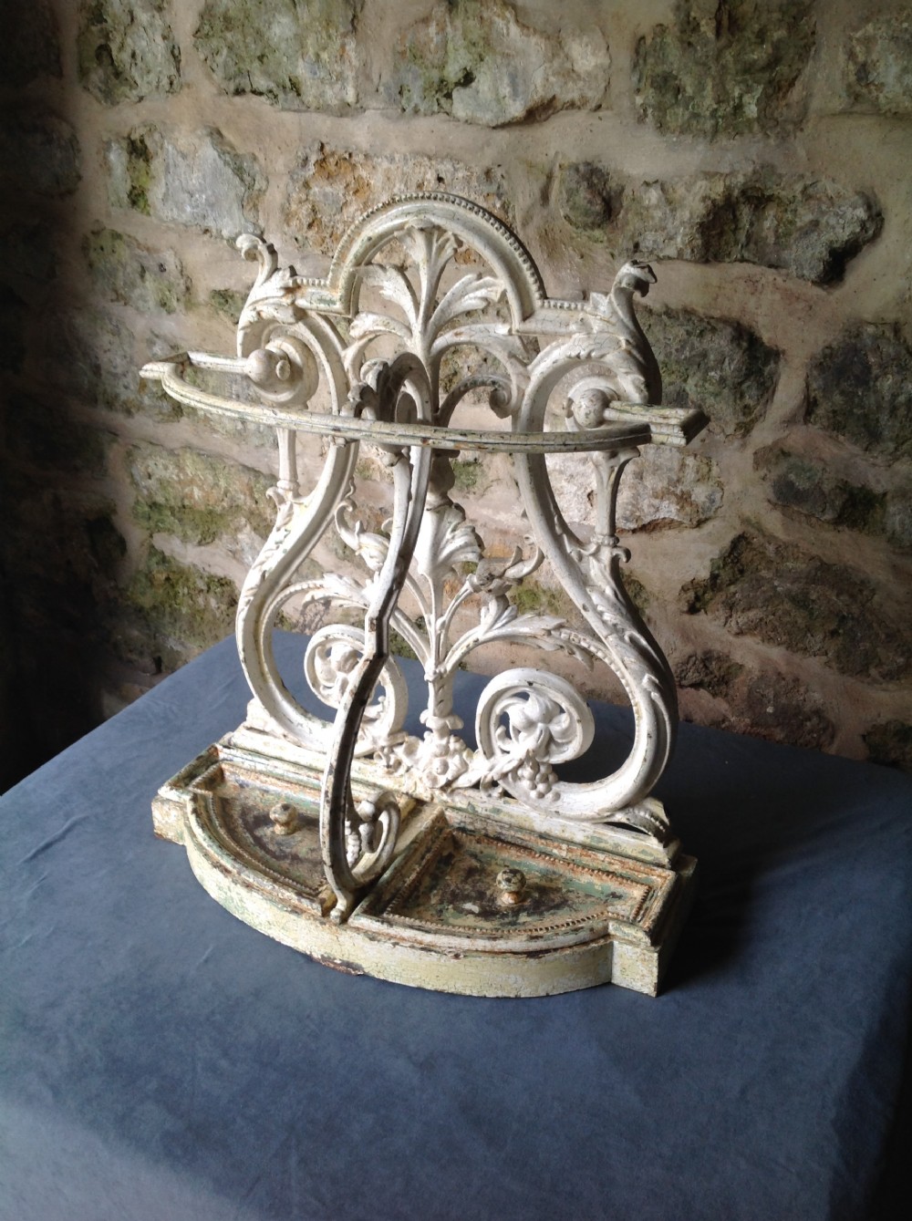 An ornate off-white painted Victorian cast iron umbrella stand with botanical scrollwork and a twin drip tray base. View II