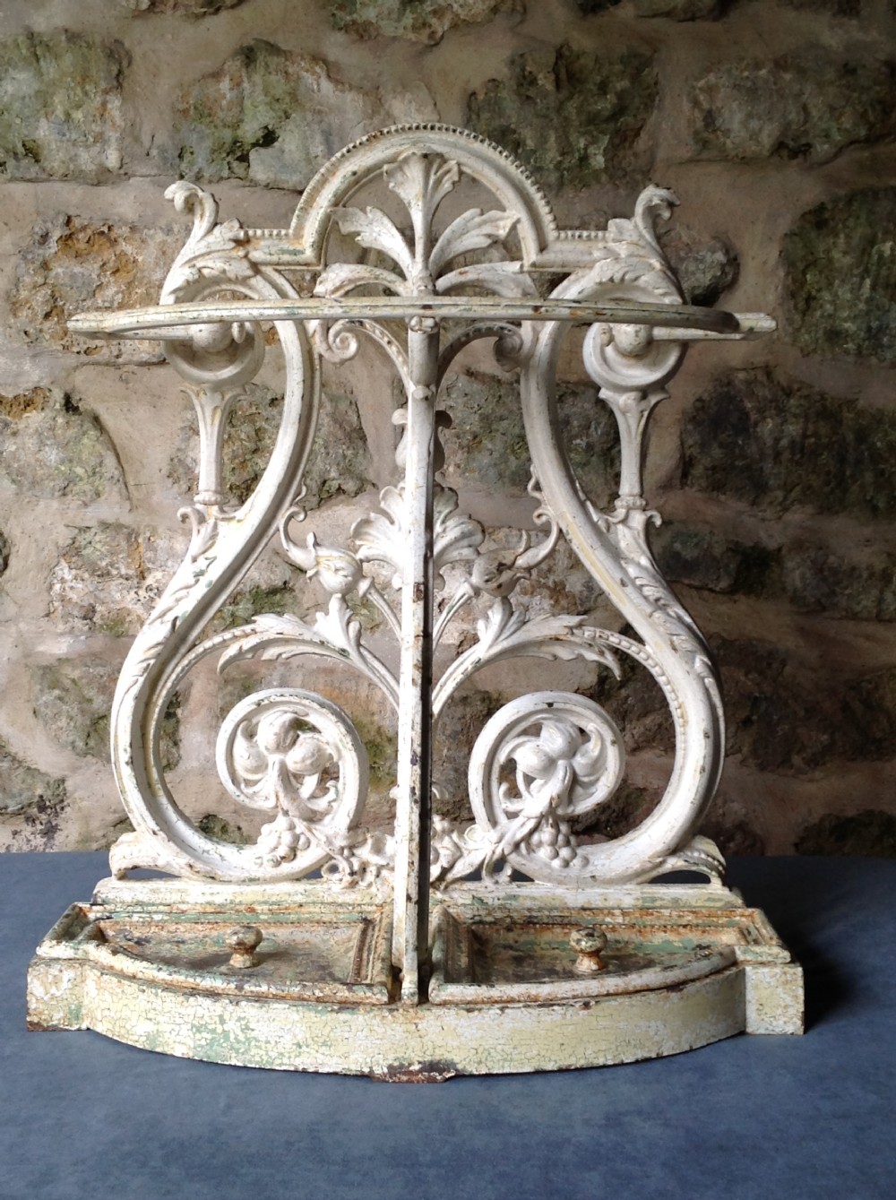 An ornate off-white painted Victorian cast iron umbrella stand with botanical scrollwork and a twin drip tray base. View IV