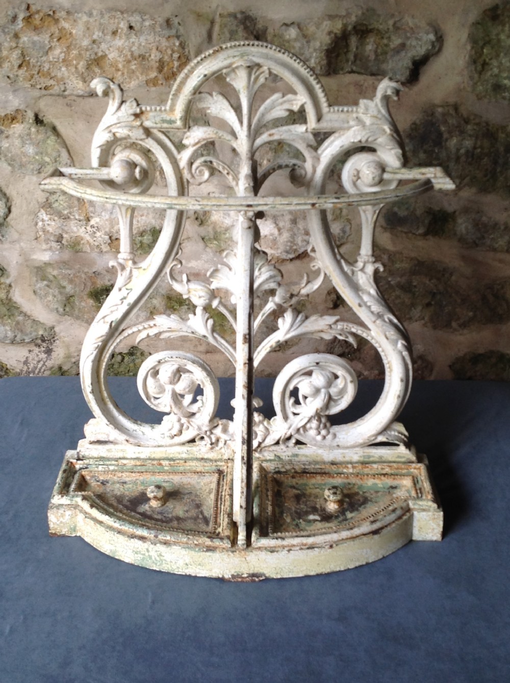 An ornate off-white painted Victorian cast iron umbrella stand with botanical scrollwork and a twin drip tray base. View V