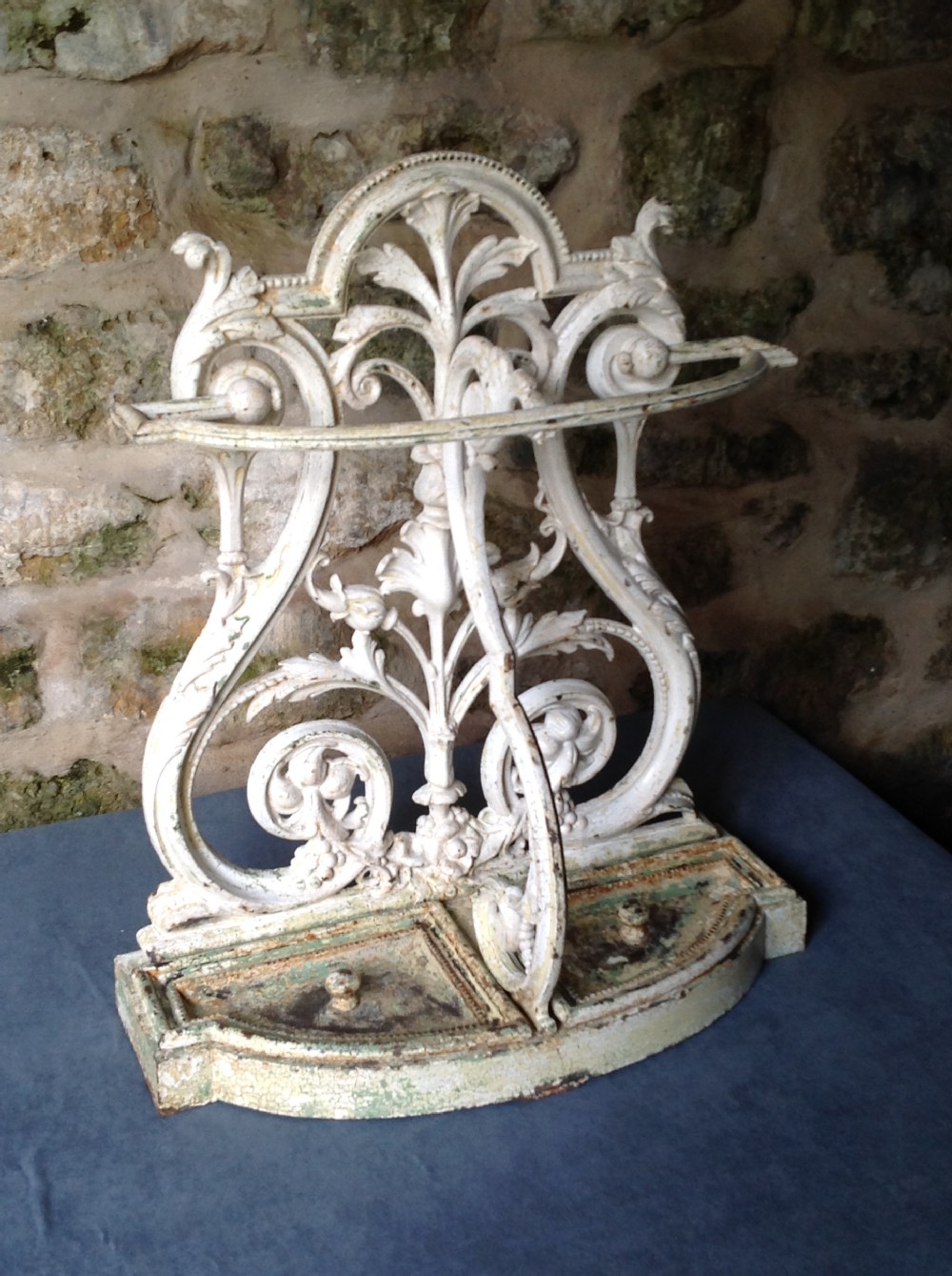 An ornate off-white painted Victorian cast iron umbrella stand with botanical scrollwork and a twin drip tray base. View VI