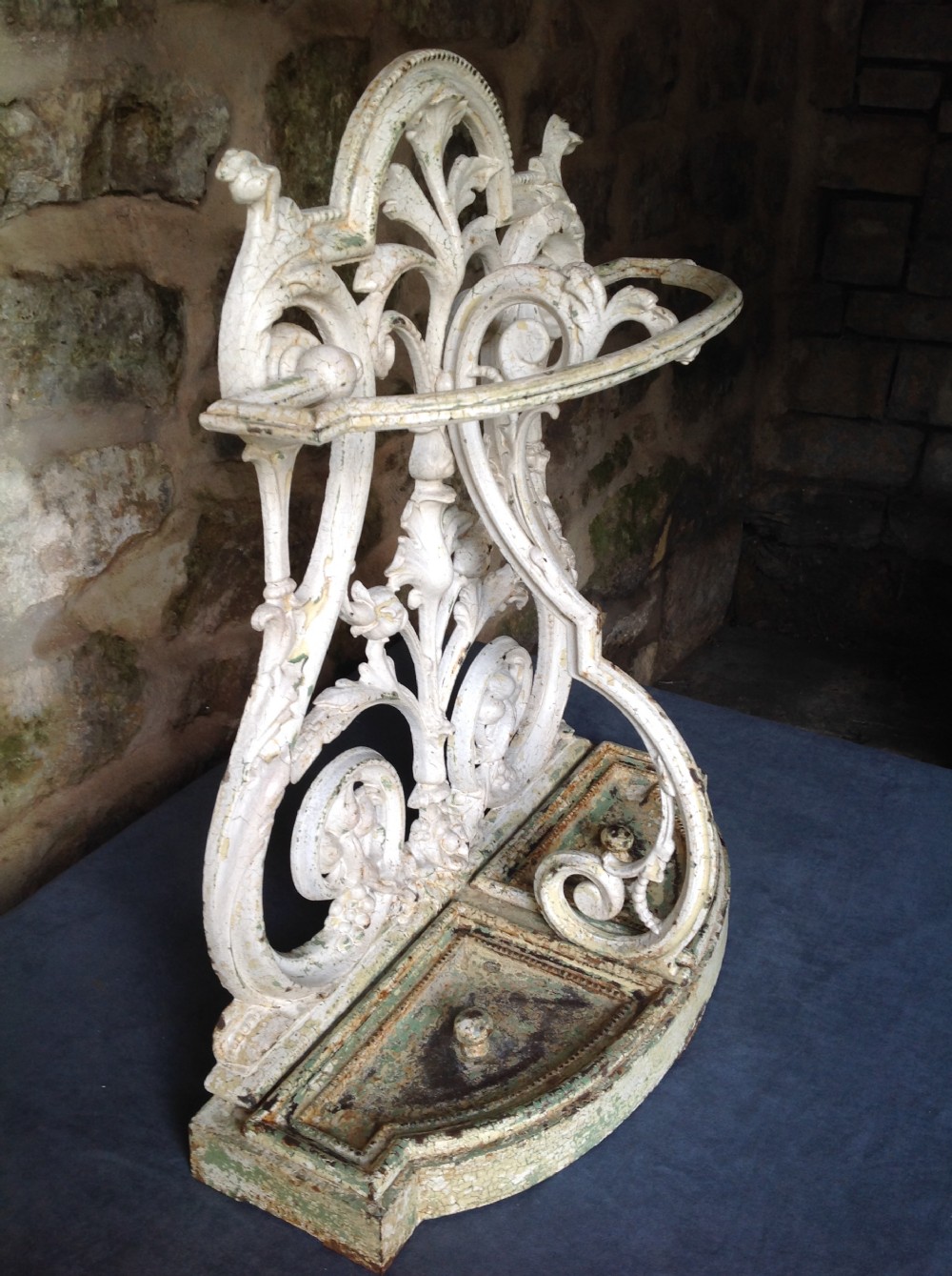 An ornate off-white painted Victorian cast iron umbrella stand with botanical scrollwork and a twin drip tray base. View VII