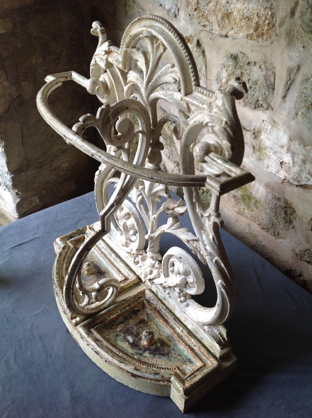 An ornate off-white painted Victorian cast iron umbrella stand with botanical scrollwork and a twin drip tray base. View XII