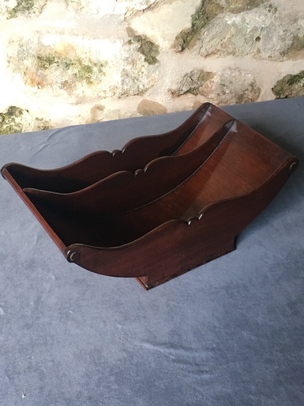 A dark mahogany Georgian cheese coaster featuring a crescent-shaped body with a central divider and scrolled ends set upon a rectangular base.