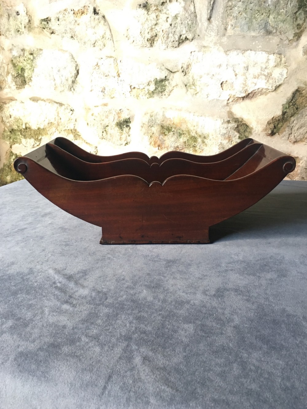 A dark mahogany Georgian cheese coaster featuring a crescent-shaped body with a central divider and scrolled ends set upon a rectangular base. View III