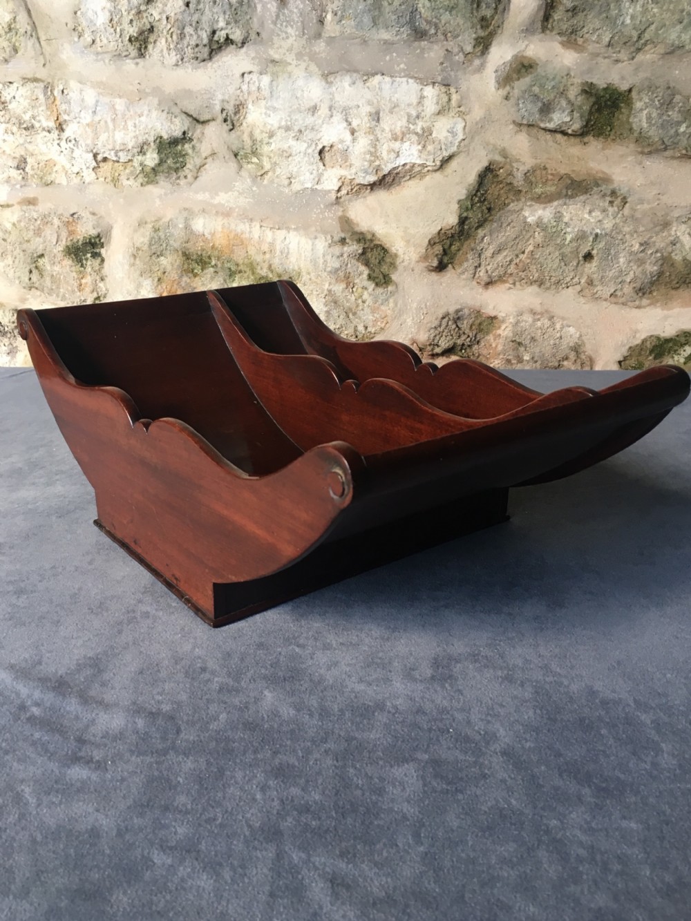 A dark mahogany Georgian cheese coaster featuring a crescent-shaped body with a central divider and scrolled ends set upon a rectangular base. View V