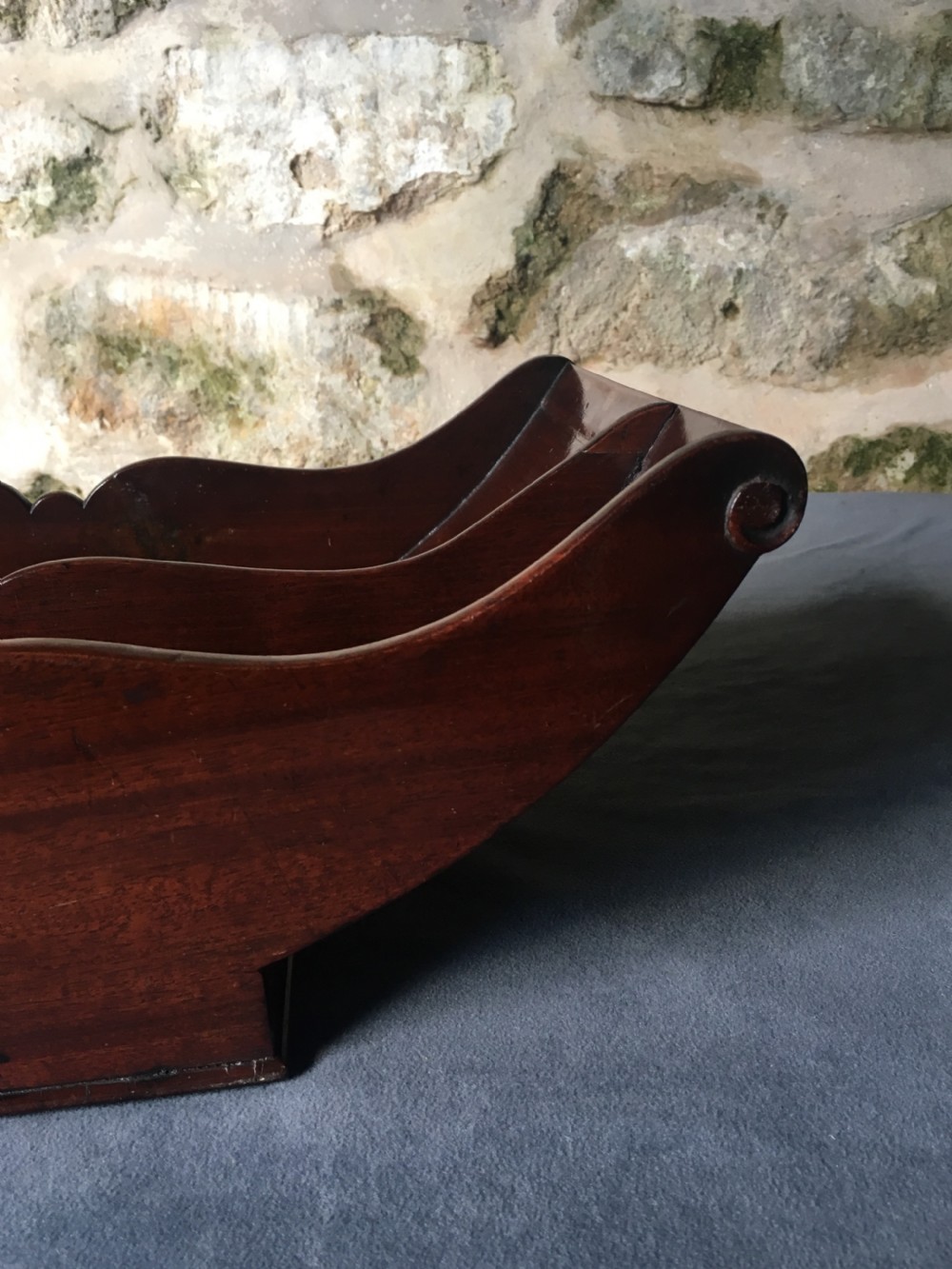 A dark mahogany Georgian cheese coaster featuring a crescent-shaped body with a central divider and scrolled ends set upon a rectangular base. View IX