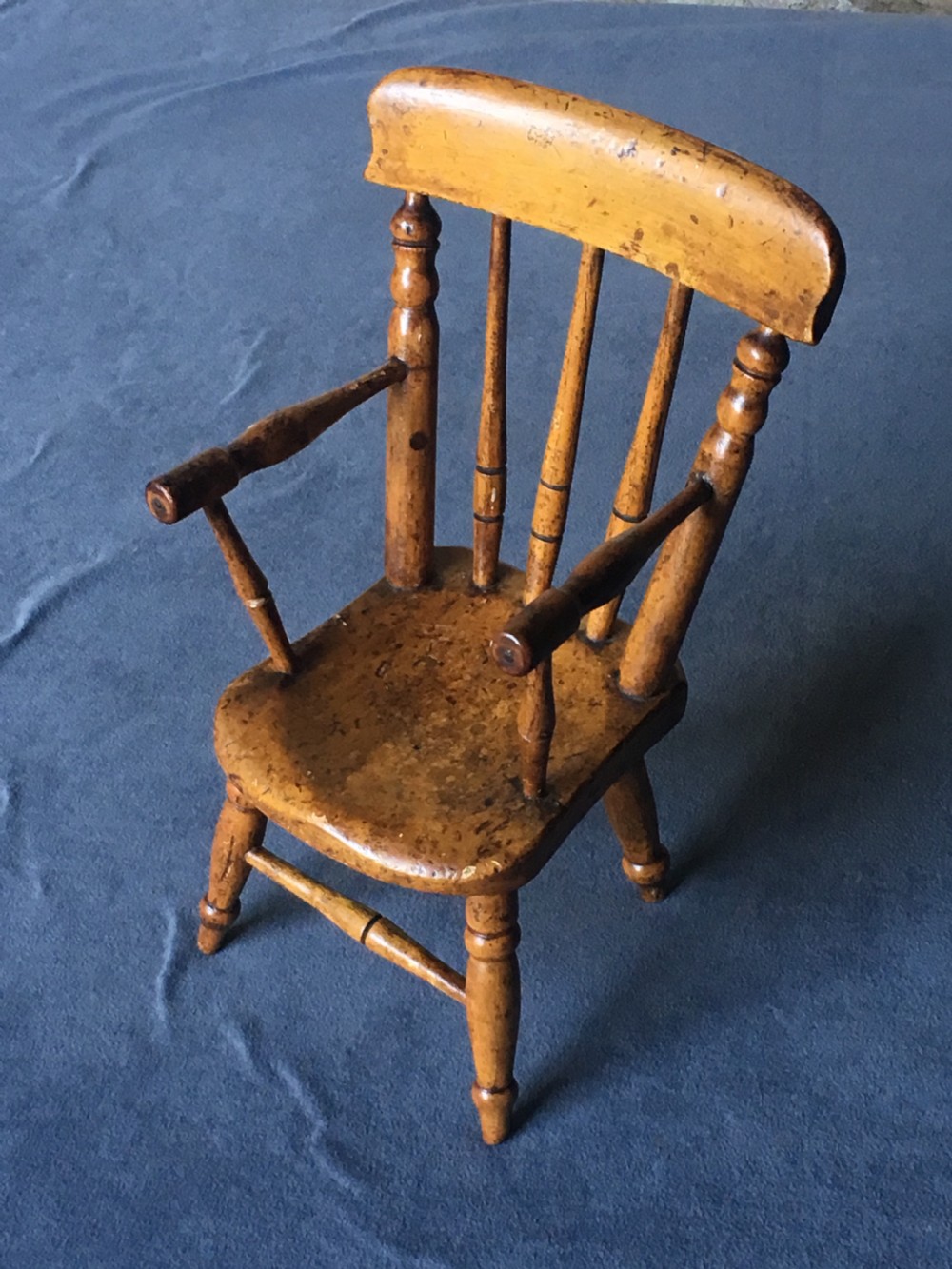 A wooden miniature Windsor armchair featuring turned spindle back supports, curved armrests, and turned legs. View II