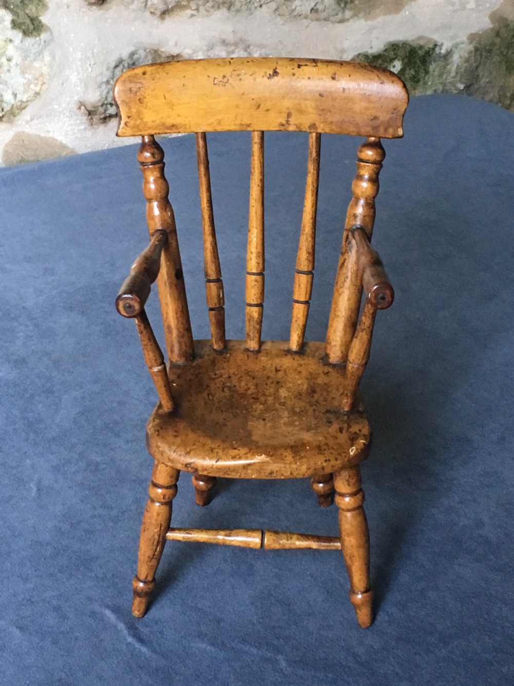 A wooden miniature Windsor armchair featuring turned spindle back supports, curved armrests, and turned legs. View III