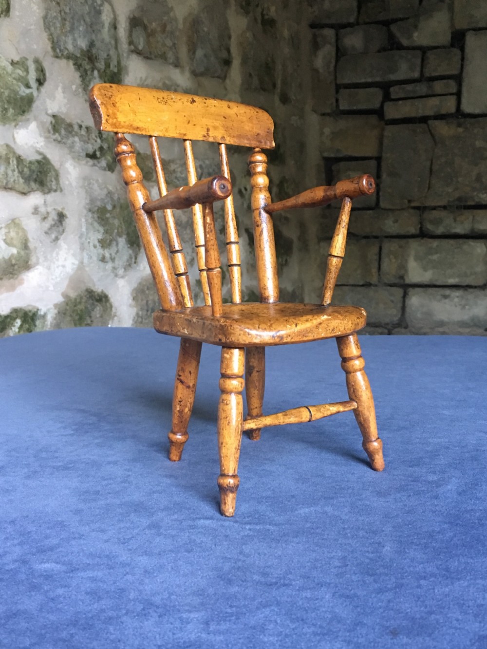 A wooden miniature Windsor armchair featuring turned spindle back supports, curved armrests, and turned legs. View IV