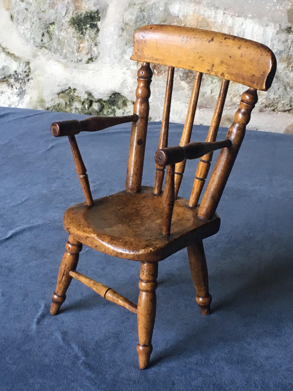 A wooden miniature Windsor armchair featuring turned spindle back supports, curved armrests, and turned legs. View V