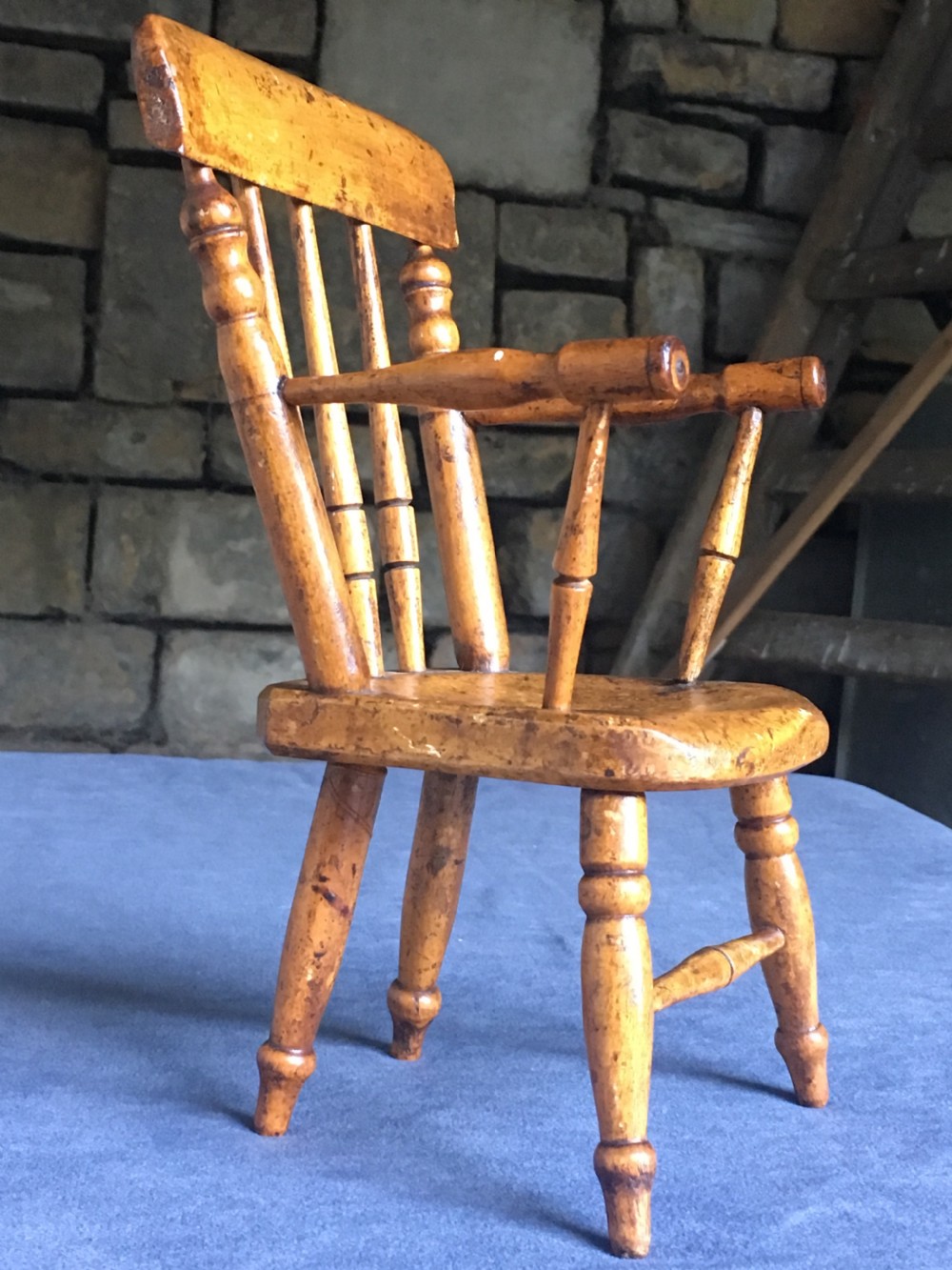 A wooden miniature Windsor armchair featuring turned spindle back supports, curved armrests, and turned legs. View VI