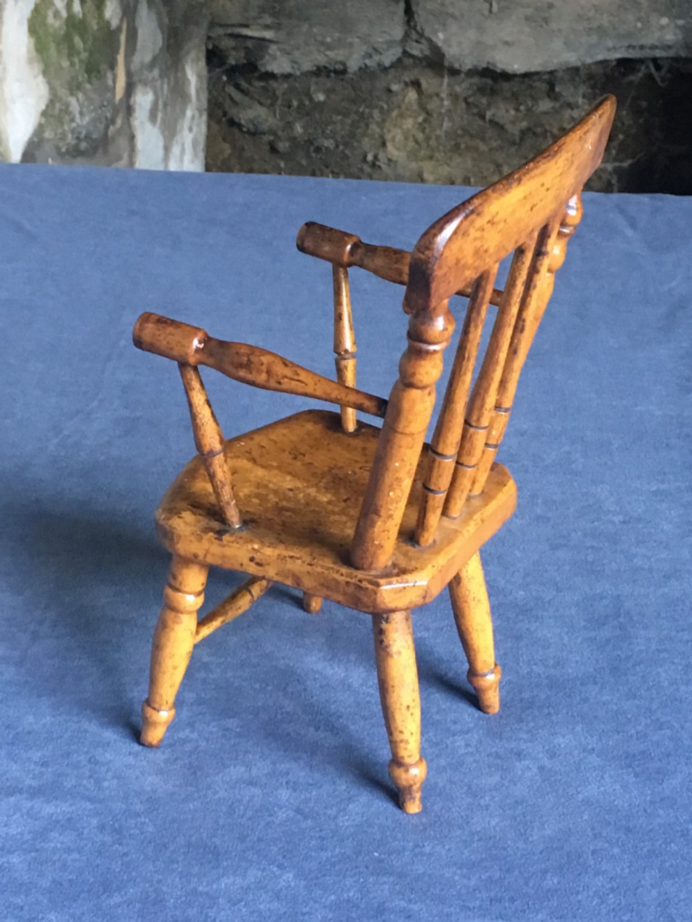 A wooden miniature Windsor armchair featuring turned spindle back supports, curved armrests, and turned legs. View X