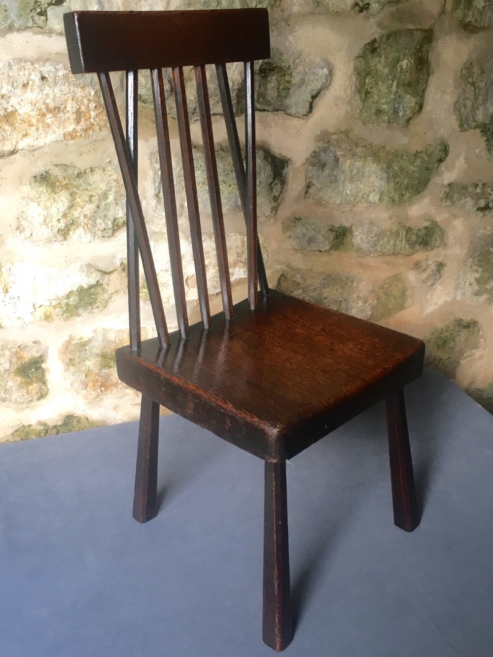 A dark oak side chair featuring a spindle back rest, solid wooden seat, and tapered splayed legs. View IX