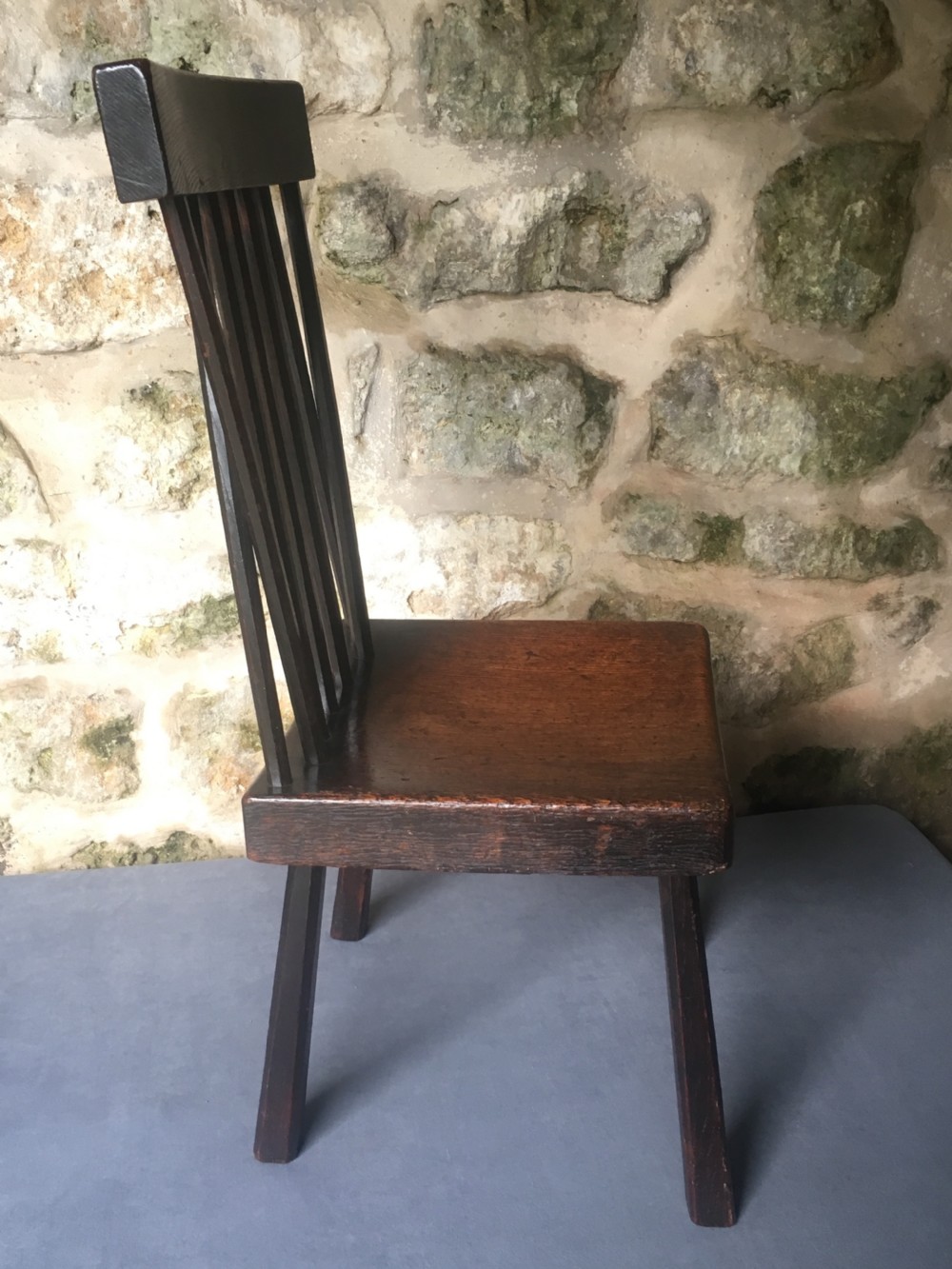 A dark oak side chair featuring a spindle back rest, solid wooden seat, and tapered splayed legs. View XI