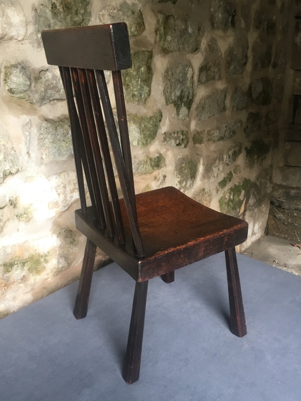 A dark oak side chair featuring a spindle back rest, solid wooden seat, and tapered splayed legs. View XII