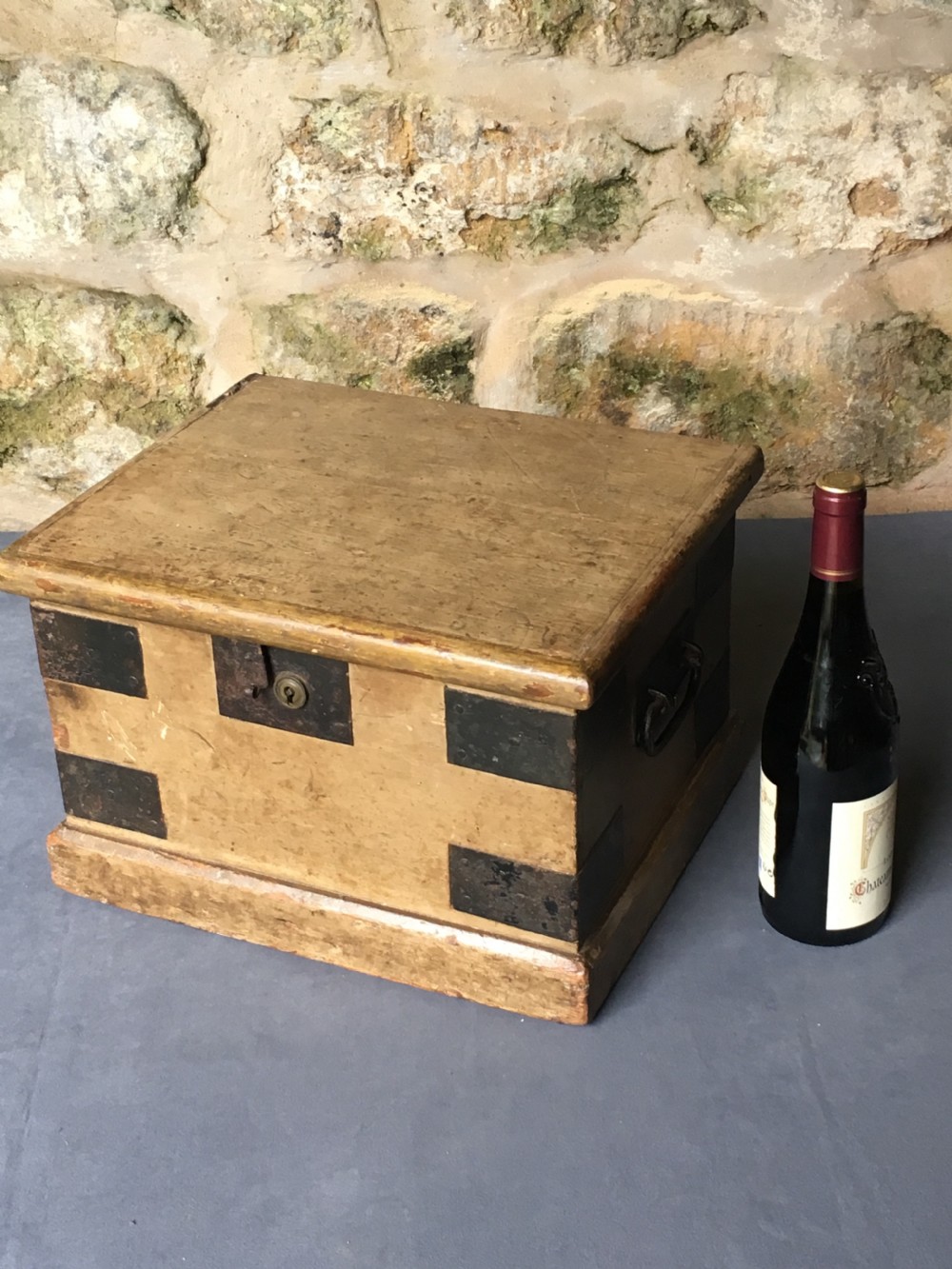 A small Victorian wooden trunk featuring an ochre painted finish, dark iron corner brackets, side handles, and a hinged lid. View II