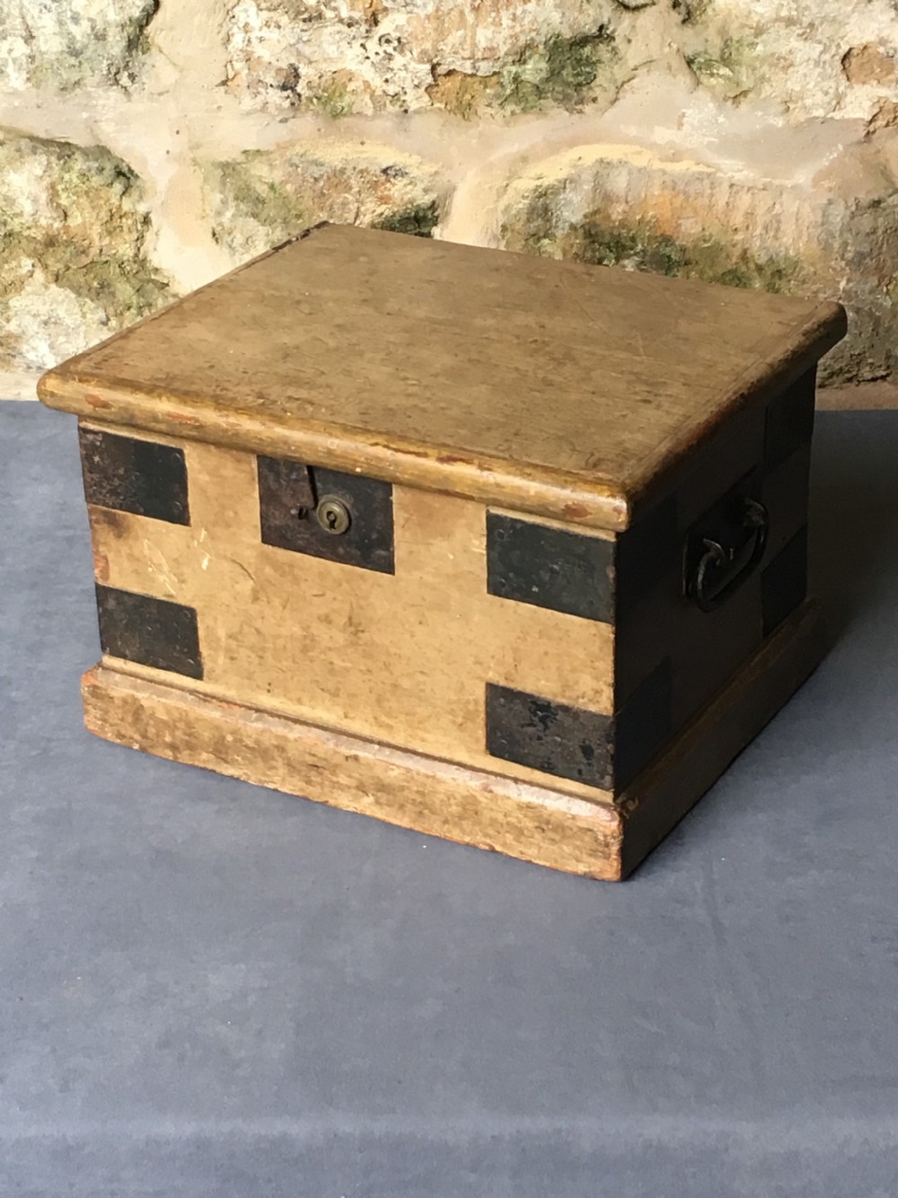 A small Victorian wooden trunk featuring an ochre painted finish, dark iron corner brackets, side handles, and a hinged lid. View III
