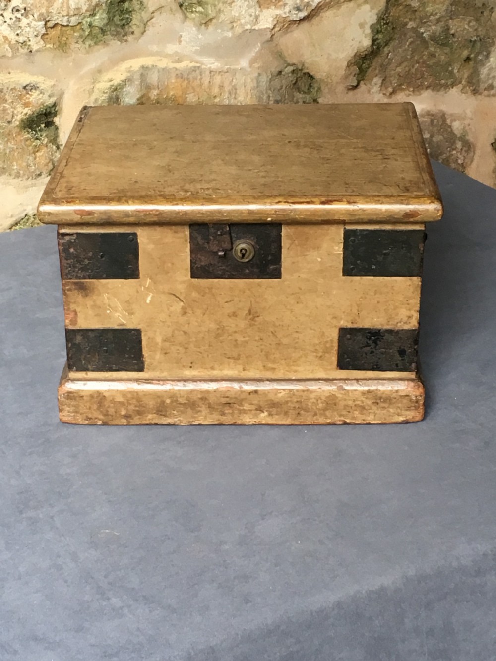 A small Victorian wooden trunk featuring an ochre painted finish, dark iron corner brackets, side handles, and a hinged lid. View IV