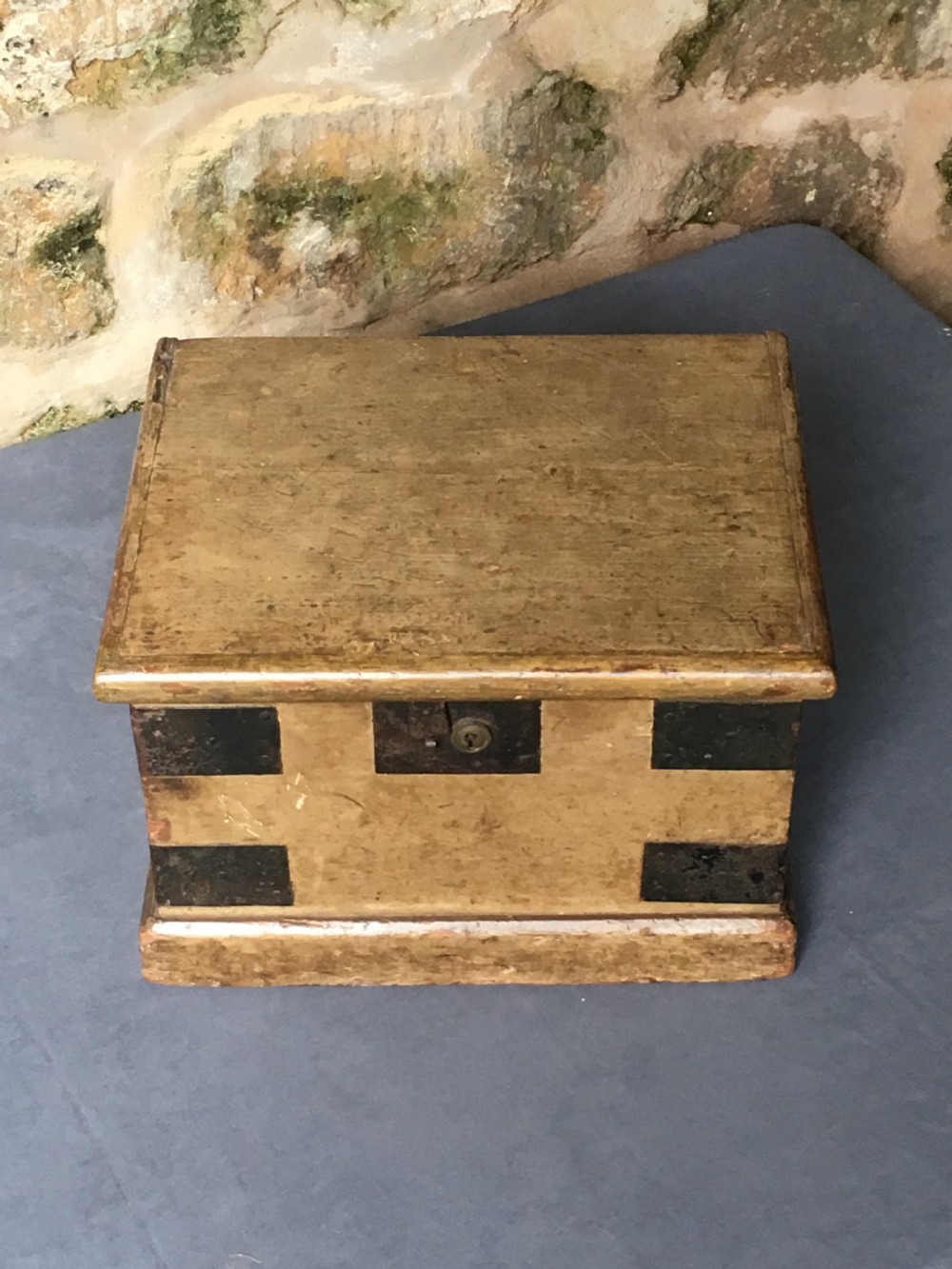 A small Victorian wooden trunk featuring an ochre painted finish, dark iron corner brackets, side handles, and a hinged lid. View V