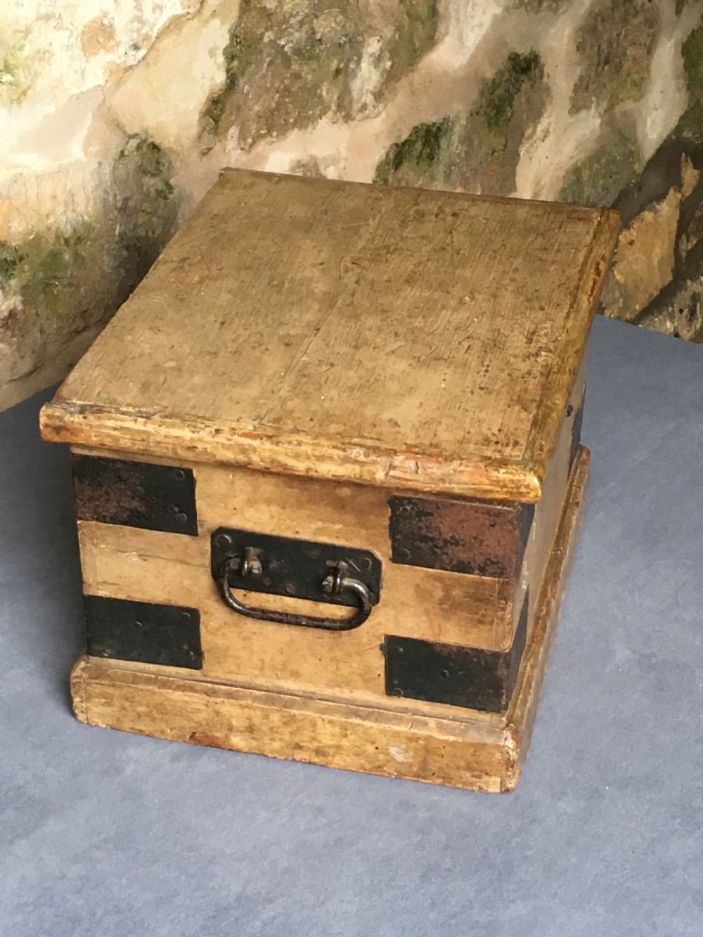 A small Victorian wooden trunk featuring an ochre painted finish, dark iron corner brackets, side handles, and a hinged lid. View VII
