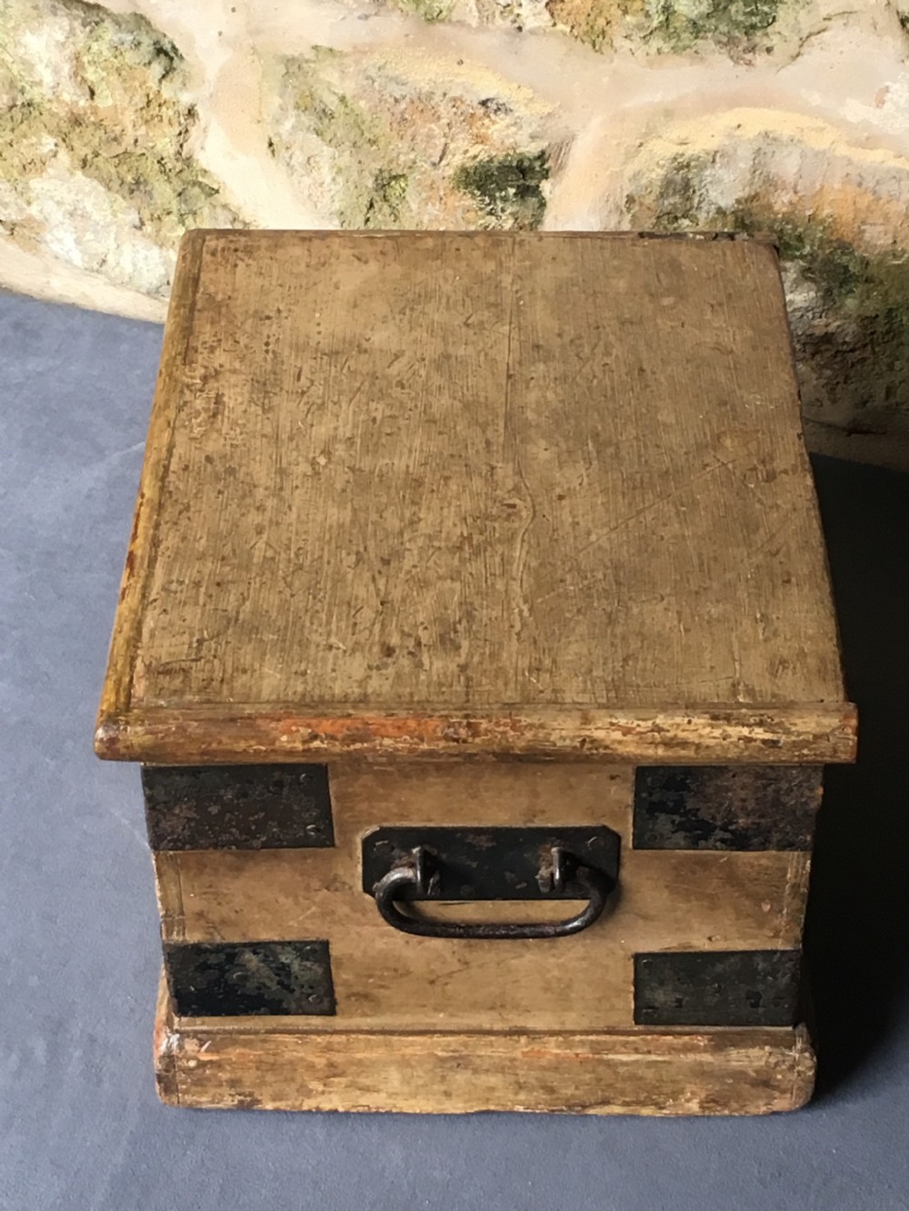 A small Victorian wooden trunk featuring an ochre painted finish, dark iron corner brackets, side handles, and a hinged lid. View XIV
