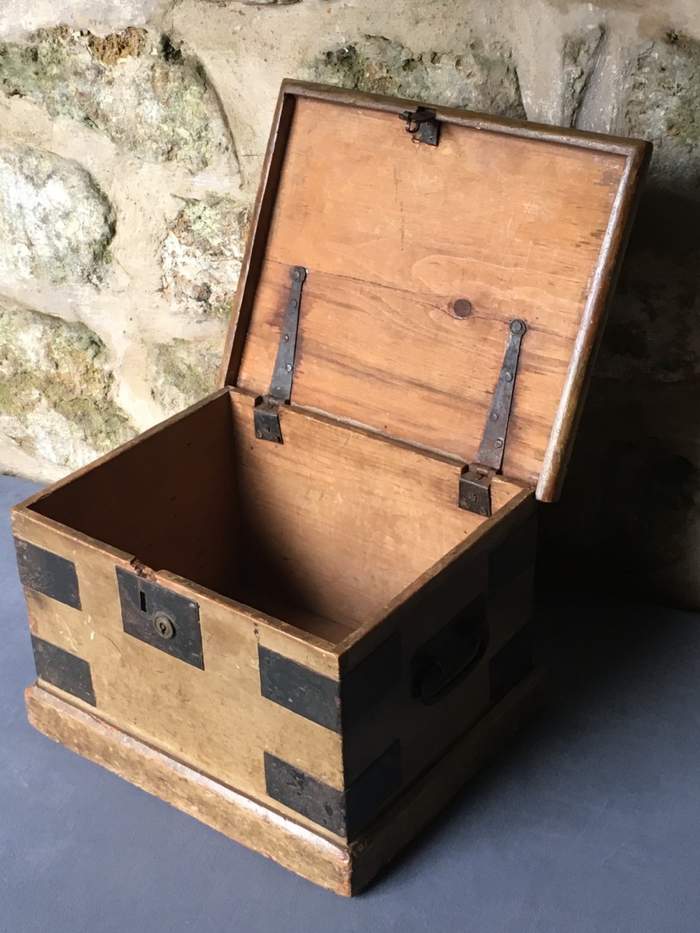 A small Victorian wooden trunk featuring an ochre painted finish, dark iron corner brackets, side handles, and a hinged lid. View XVI