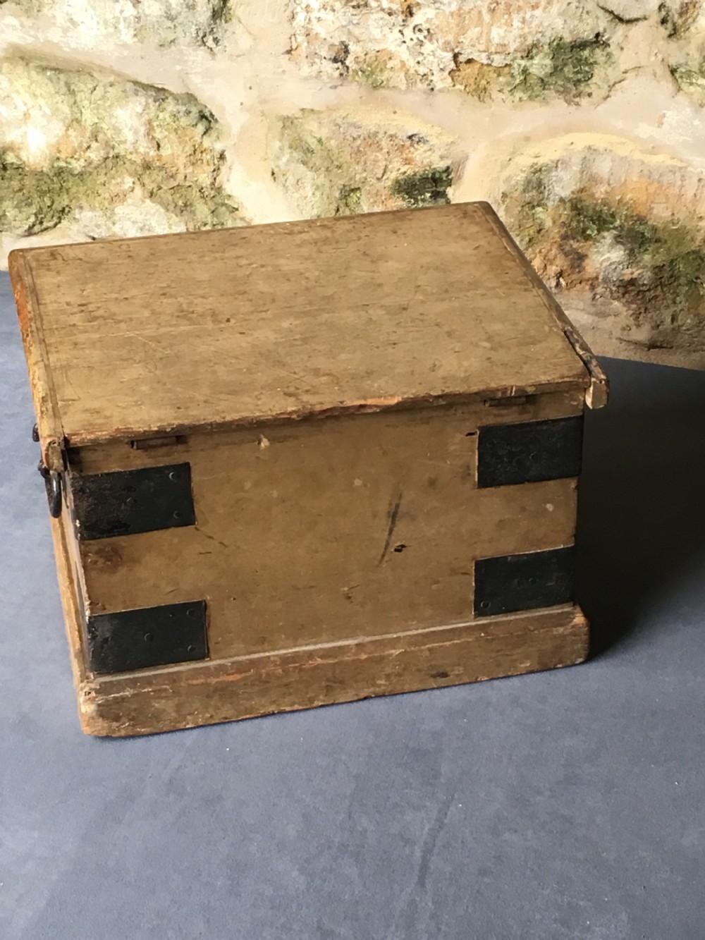 A small Victorian wooden trunk featuring an ochre painted finish, dark iron corner brackets, side handles, and a hinged lid. View XVII