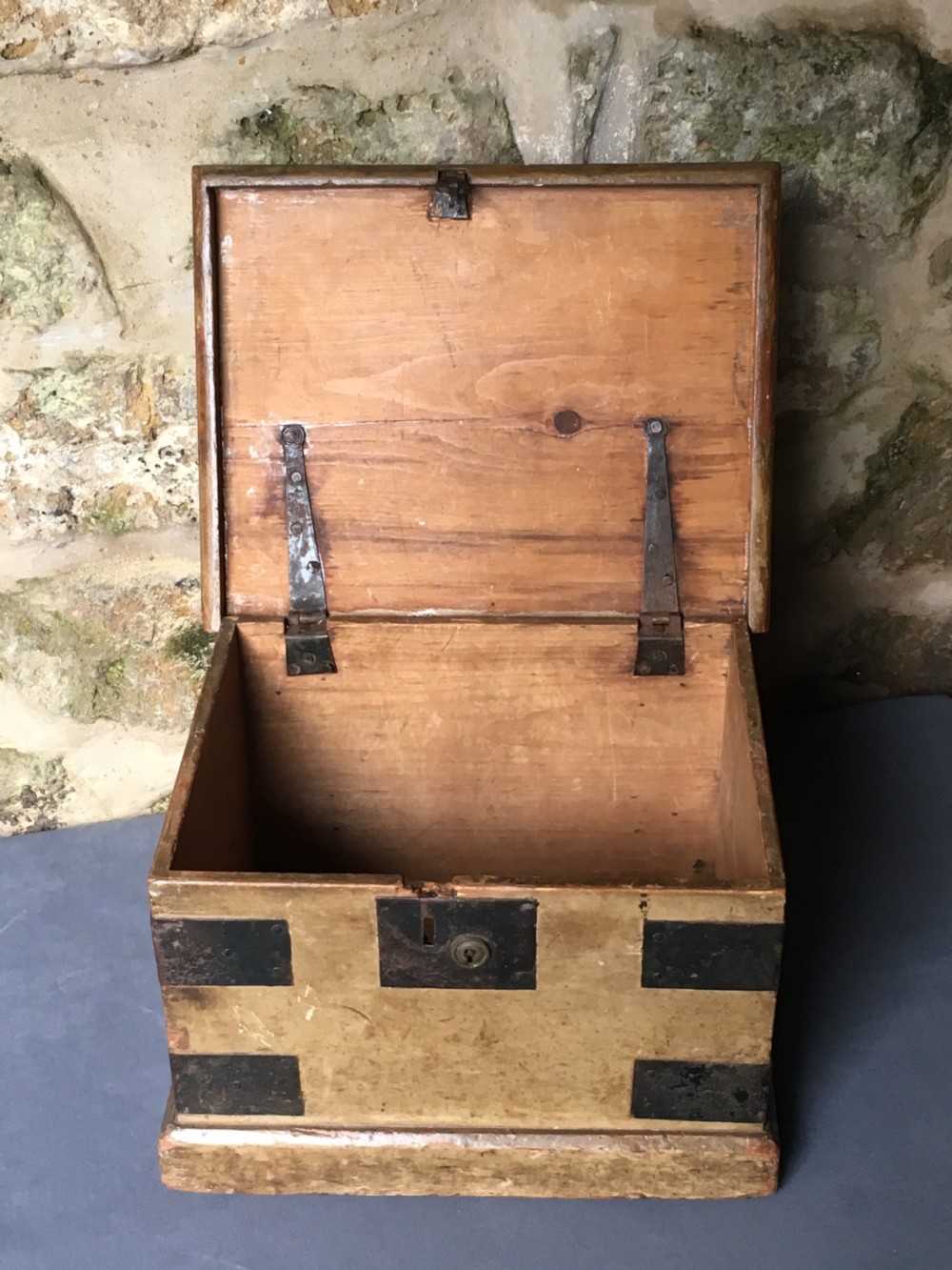 A small Victorian wooden trunk featuring an ochre painted finish, dark iron corner brackets, side handles, and a hinged lid. View XVIII