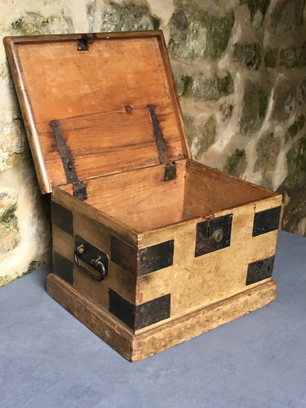 A small Victorian wooden trunk featuring an ochre painted finish, dark iron corner brackets, side handles, and a hinged lid. View XIX