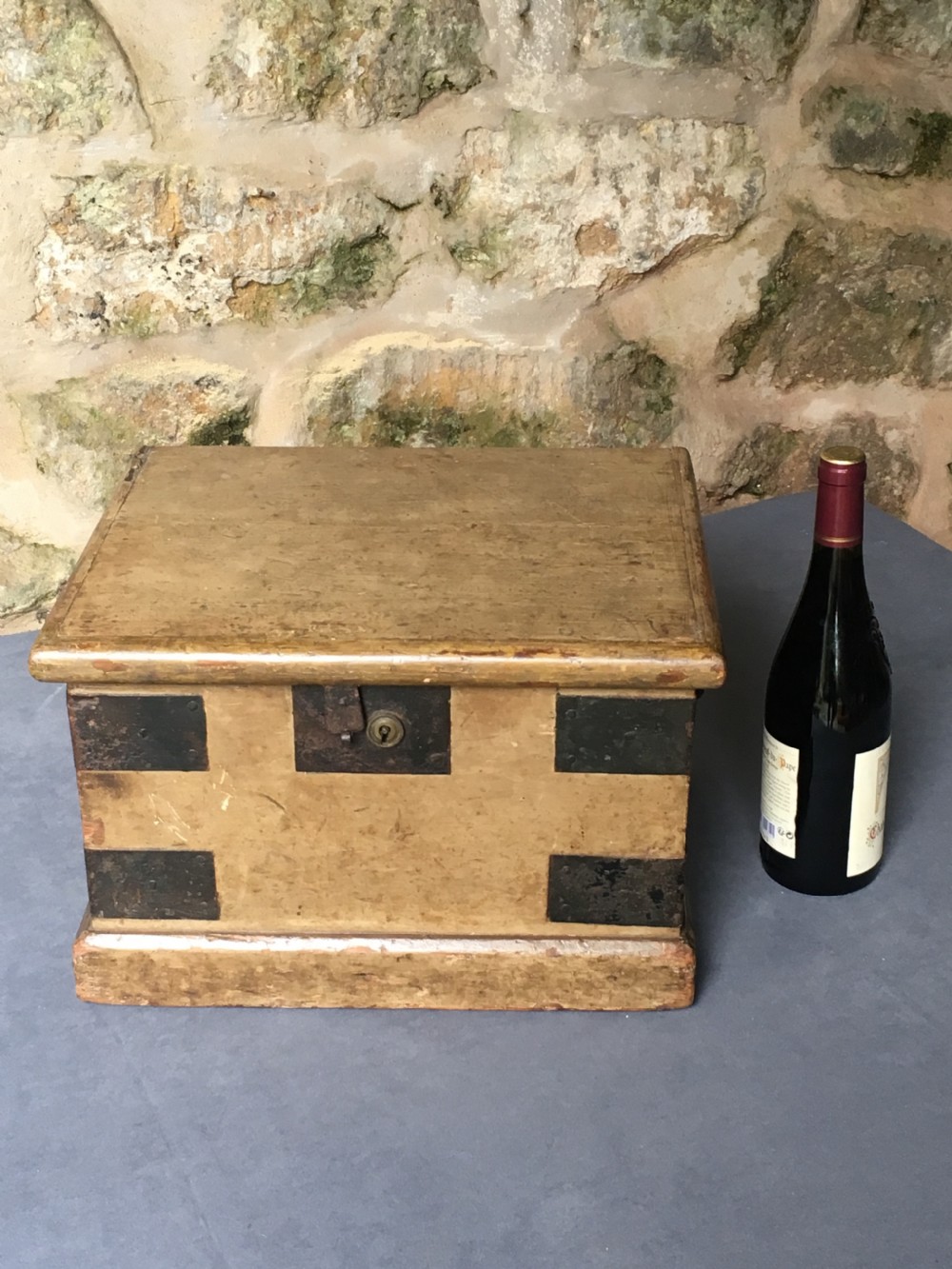 A small Victorian wooden trunk featuring an ochre painted finish, dark iron corner brackets, side handles, and a hinged lid. View XX