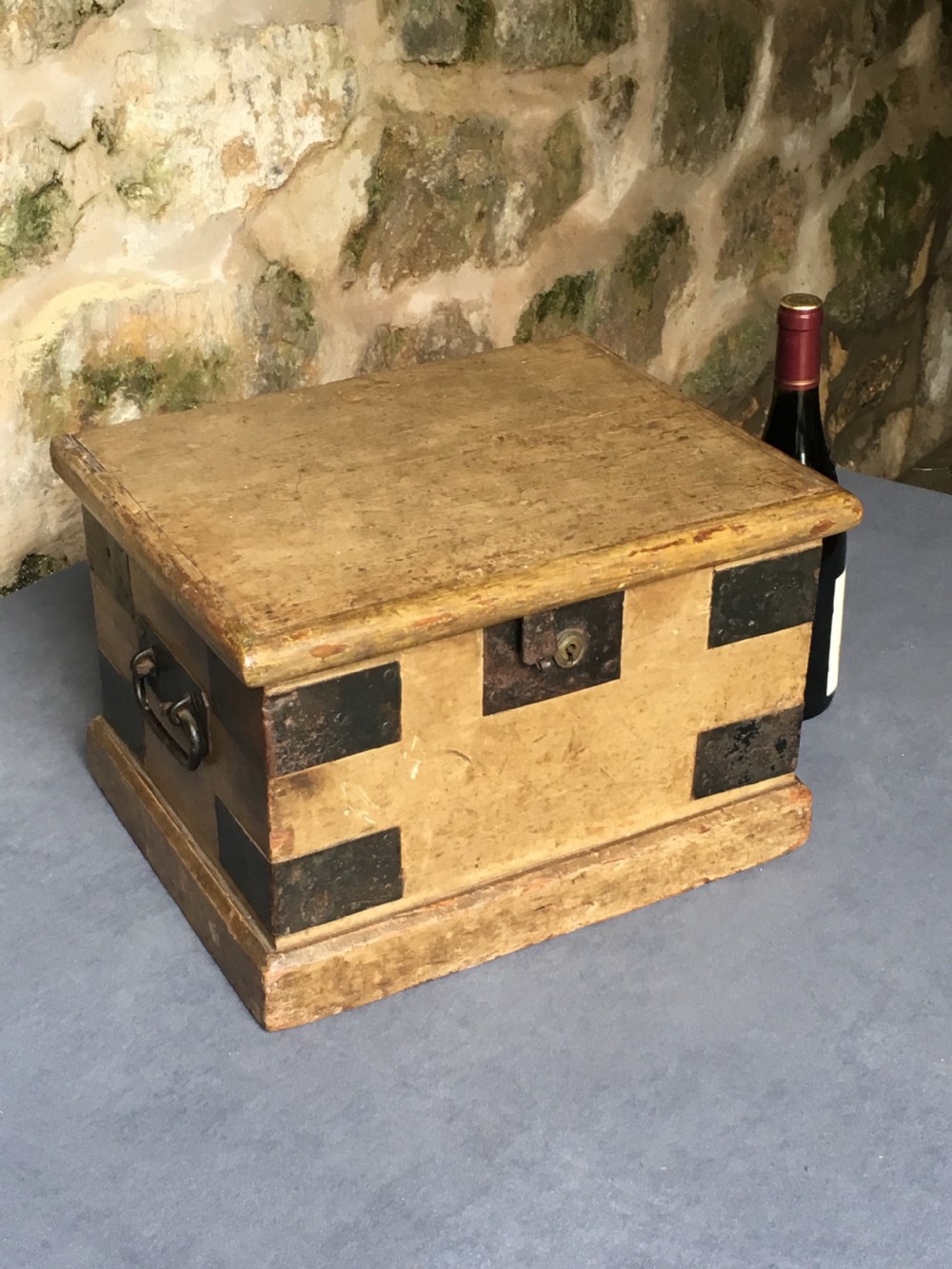 A small Victorian wooden trunk featuring an ochre painted finish, dark iron corner brackets, side handles, and a hinged lid. View XXI