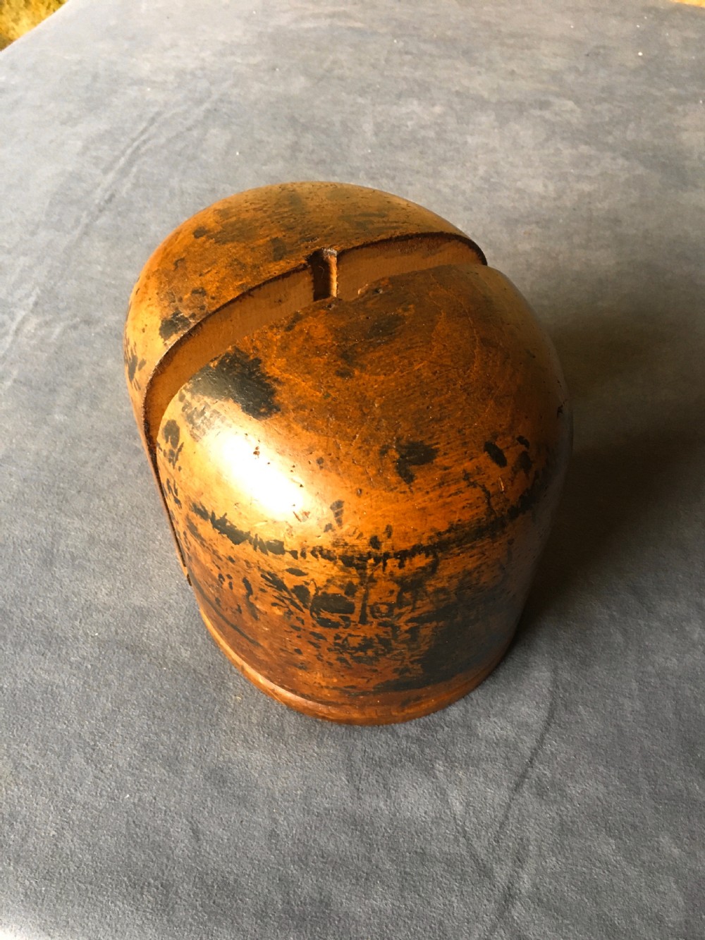 A two-piece carved wooden milliners hat block featuring a rounded dome top and a weathered brown and black painted finish. View V