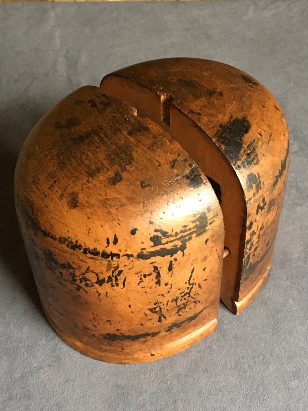 A two-piece carved wooden milliners hat block featuring a rounded dome top and a weathered brown and black painted finish. View XI