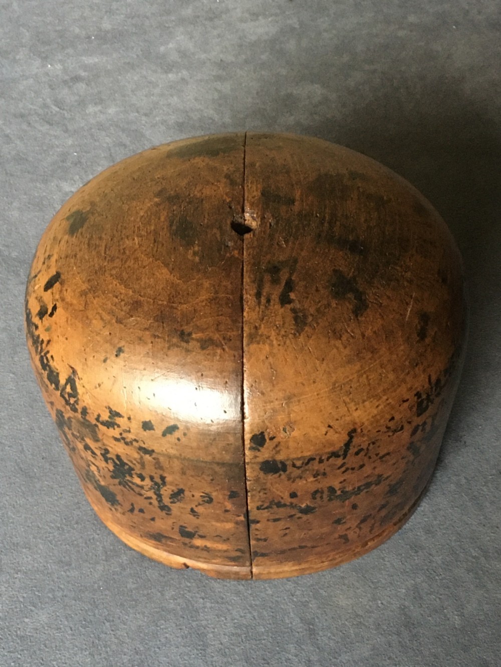 A two-piece carved wooden milliners hat block featuring a rounded dome top and a weathered brown and black painted finish. View XIV